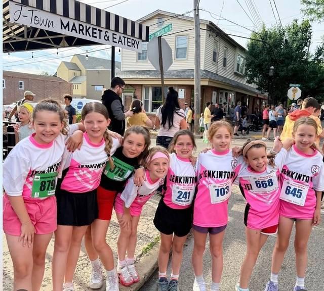 A youth team in matching shirts posing together before a 5K