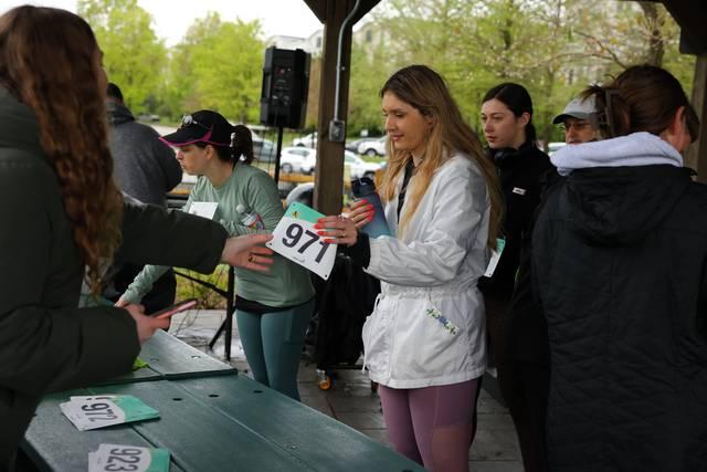A volunteer handing a bib across the packet pickup table