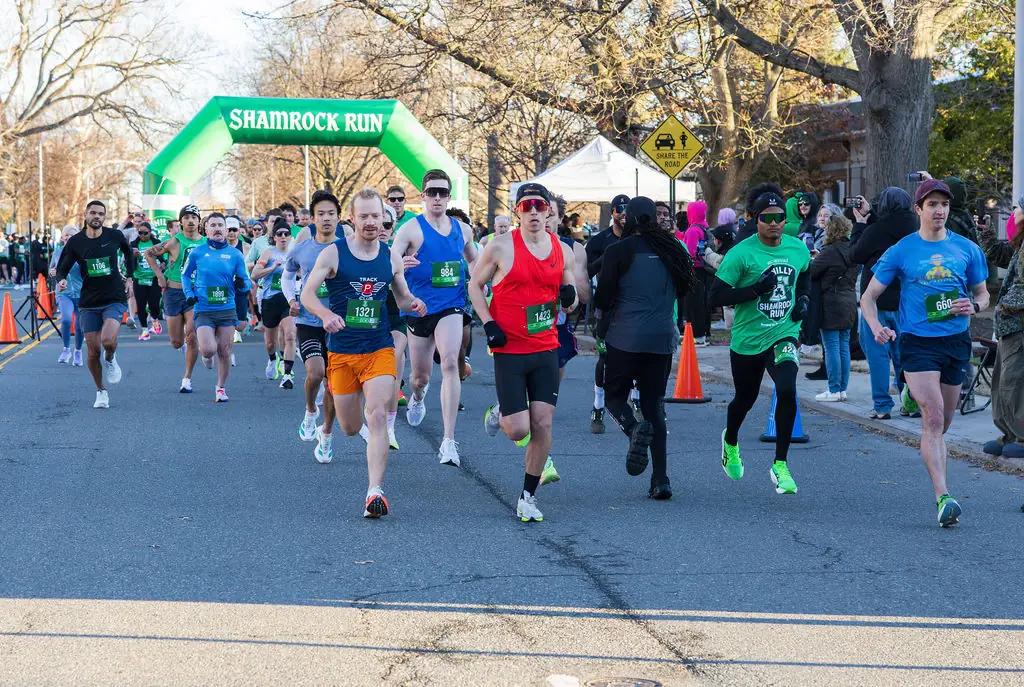 Runners passing under the green Shamrock Run inflatable arch at the start line